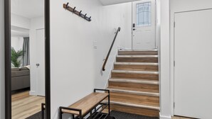 A staircase with wooden steps and a handrail, leading to a door with a glass panel. - 2BR | Warm | King Bed | Downtown | Expo Centre | Roger's Place (Edmonton)