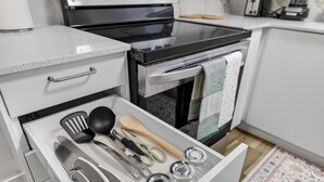 A kitchen with a stainless steel oven, a microwave, and a drawer with kitchen utensils. - 2BR | Warm | King Bed | Downtown | Expo Centre | Roger's Place (Edmonton)