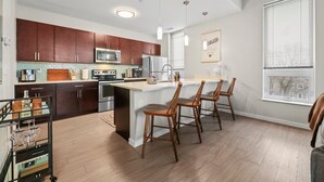 Una cocina moderna con armarios de madera, electrodomésticos de acero inoxidable y una isla central con taburetes de bar.