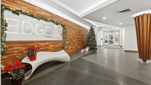 Una moderna zona de recepción con un muro de madera, un gran cartel que dice "EDGE 32" y decoración navideña.