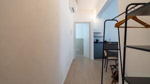 Ein schmaler Flur, der in einen Küchenbereich mit integriertem Sitzbänken und einer Kleiderstange führt.