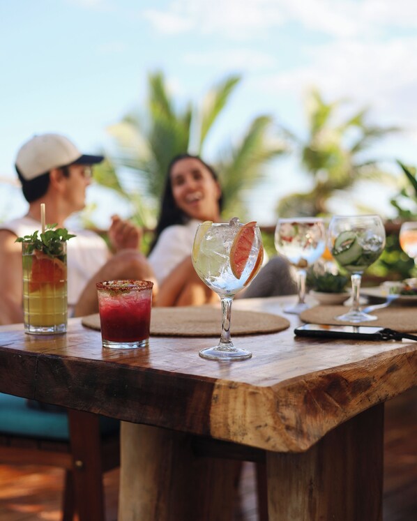 A wooden table with drinks and a smartphone. - Casa Hayhu Beach (Mahahual)