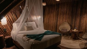 A cozy room with a bed, a small round table with a candle, and a woven chair. - Casa Hayhu Beach (Mahahual)