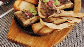 A wooden serving board with grilled meat, bread, and guacamole. - Casa Hayhu Beach (Mahahual)