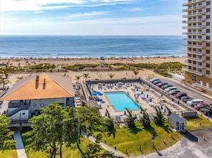A hotel with a swimming pool, beach access, and a view of the ocean. - A Wave From it All | Screened Porch Outdoor Dining (Ocean Pines)