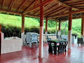 An outdoor covered patio with a tiled floor, a table with chairs, and a grill. - Country house with private pool for 26 people, 45 minutes from Pereira. (Pereira)
