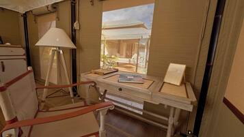 A compact room with a desk, chair, lamp, and a window with a view of a house.