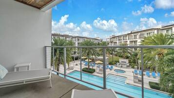 A balcony with a view of a swimming pool and a resort area.