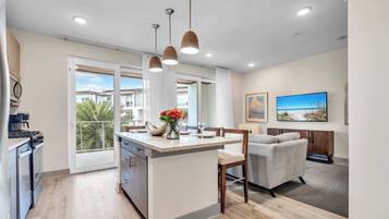 A modern kitchen with a central island, pendant lighting, and a view of a residential area.