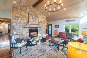 Ein gemütliches Wohnzimmer mit Kamin aus Stein, Holzboden und bequemen Sitzmöglichkeiten.