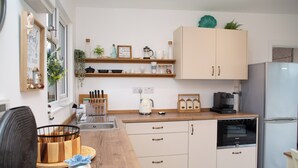 Una cucina moderna con mobili bianchi, un piano di lavoro in legno e un frigorifero in acciaio inossidabile.
