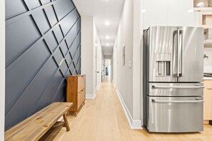 Eine moderne Küche mit einem Edelstahl-Kühlschrank, einer Holzbank und einer Wand mit geometrischen Mustern.