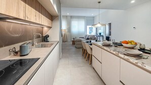 Ett modernt kök med en inbyggd spis, en diskho och en matplats med ett bord och stolar.