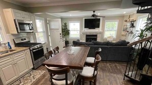 A modern kitchen with white cabinets, a wooden dining table, and a built-in oven.