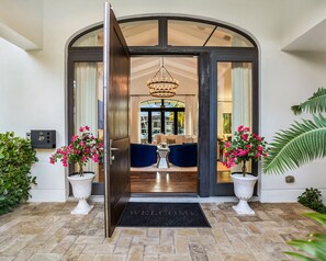 A modern entrance with a welcoming mat, two potted plants, and a view into a well-lit interior space. - Private Waterfront Luxury Villa | Resort-Style Living & Privacy (Fort Lauderdale)