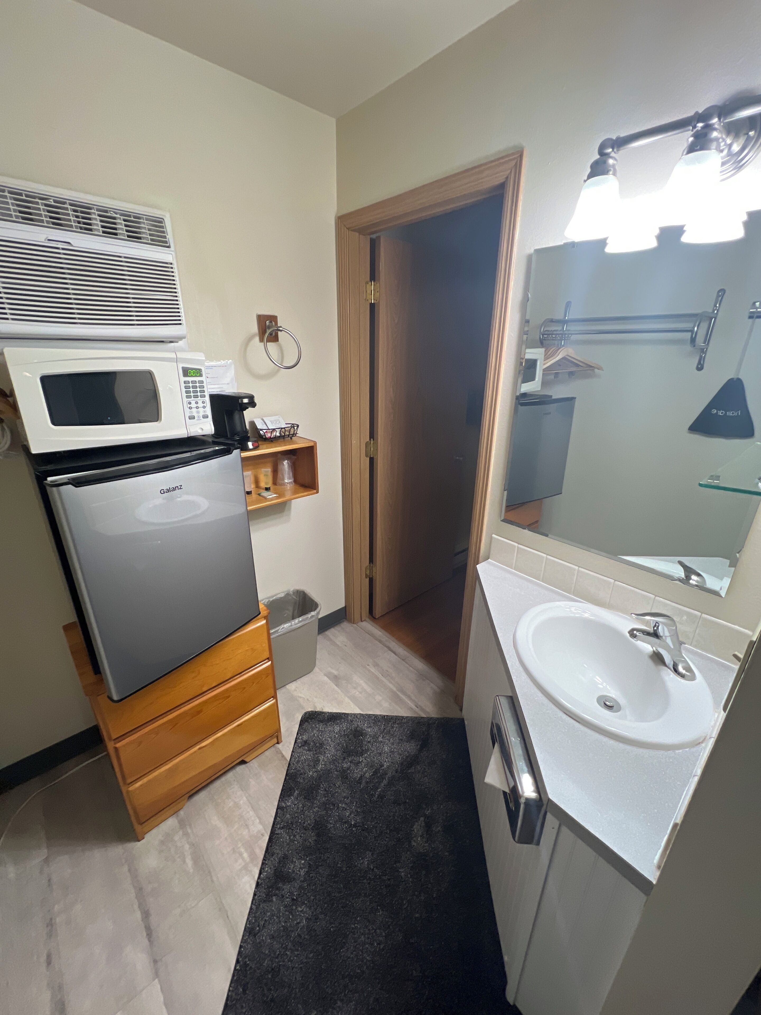 A compact kitchenette with a microwave, refrigerator, and sink.