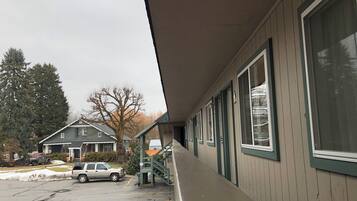 A motel with a covered walkway, a parking lot, and a neighboring house.