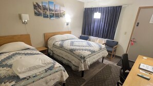 Una camera d'albergo con due letti, una scrivania in legno, una sedia, un tavolo e una finestra con tende.