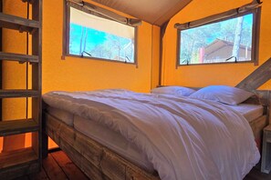 A bed with white bedding in a room with wooden beams and two windows. - Eco Camping | Tente Lodge tout confort | Piscine (Saint-Laurent-du-Verdon)