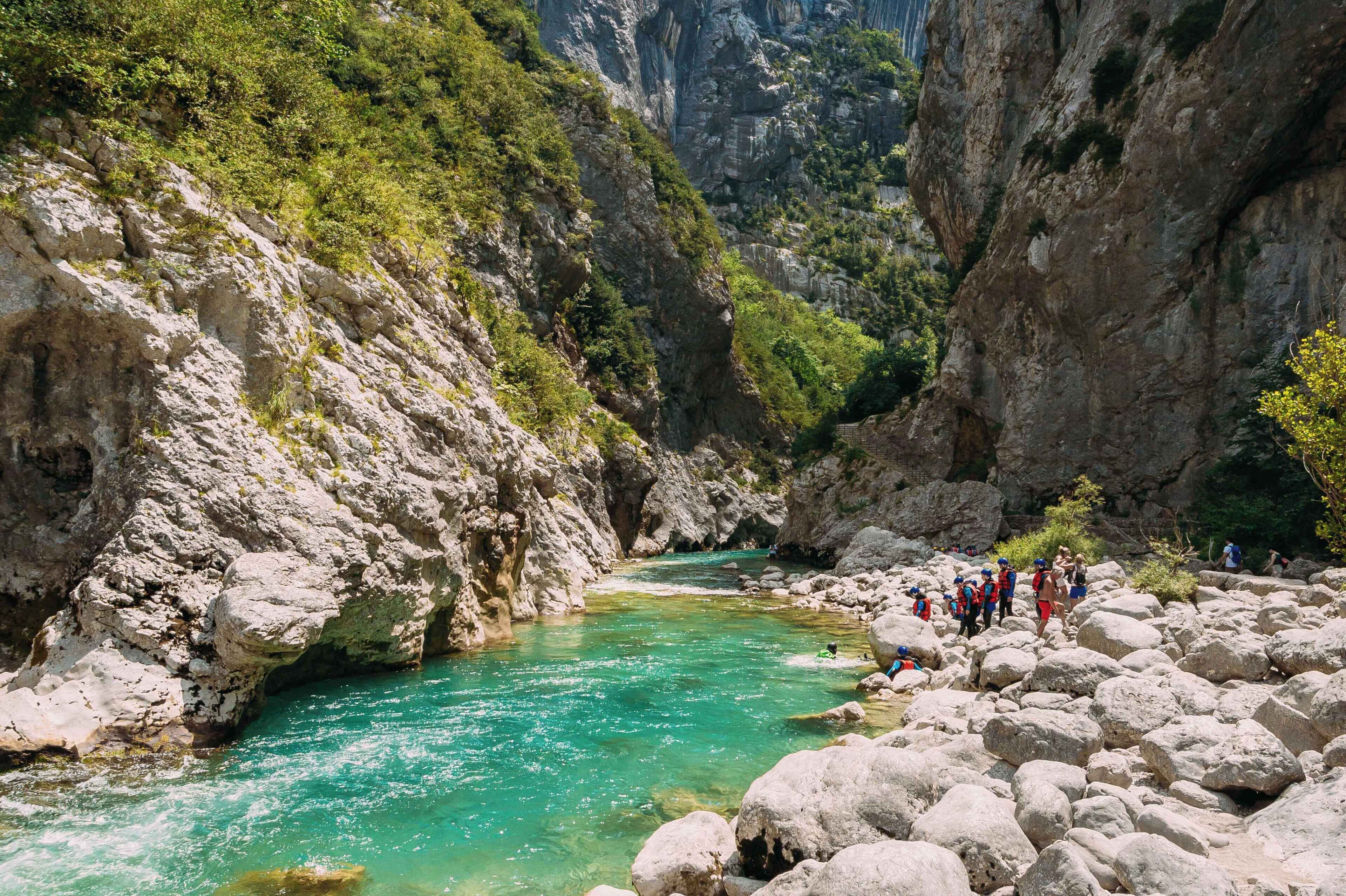 Un lit de rivière rocheux aux eaux claires, bordé de falaises abruptes et d’une végétation clairsemée.