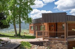 Eine moderne Holzhütte mit Steinfundament und einem Balkon mit Blick auf eine reizvolle Landschaft.