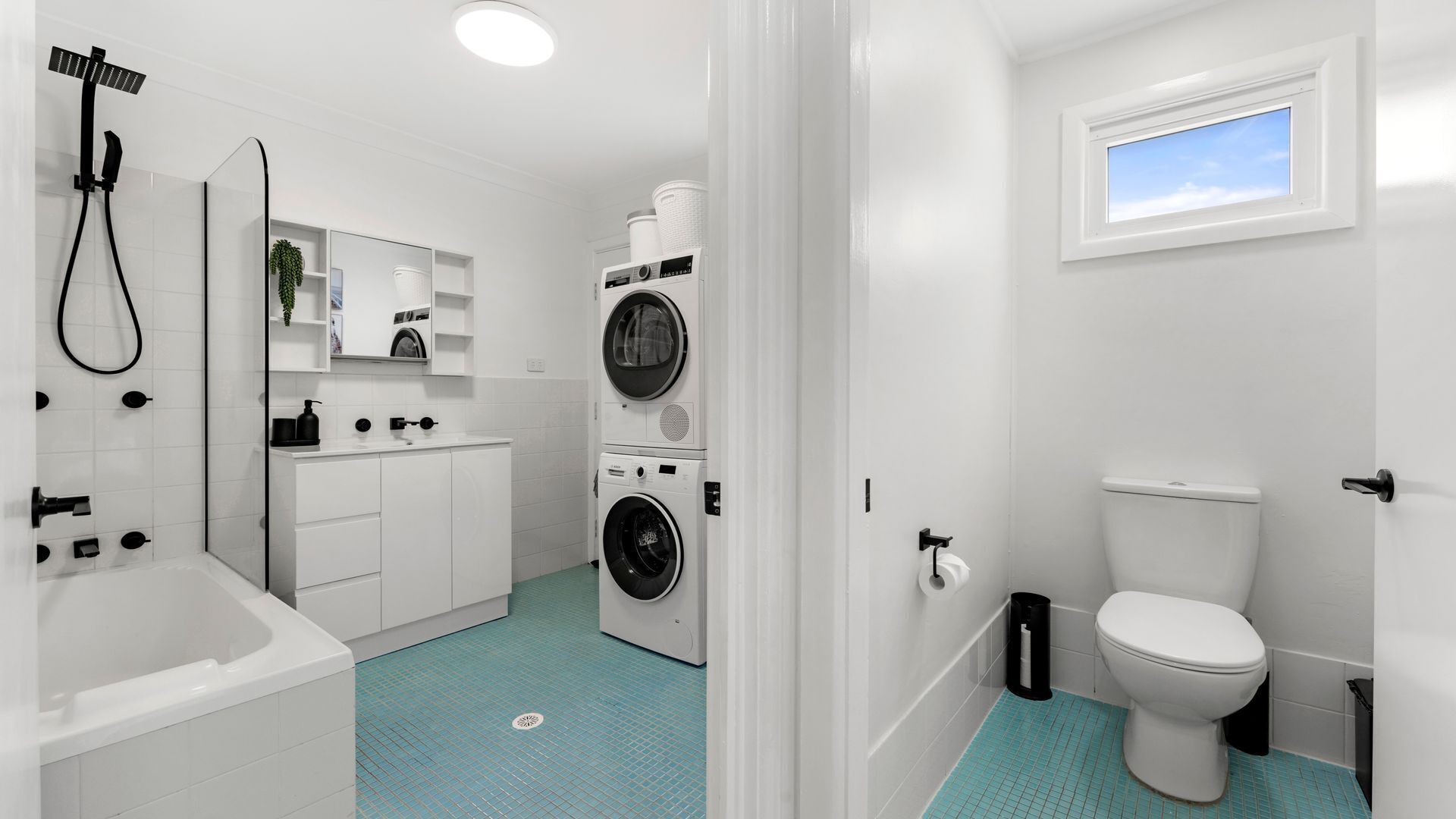 A modern bathroom with a bathtub, a shower, a toilet, and a washing machine.