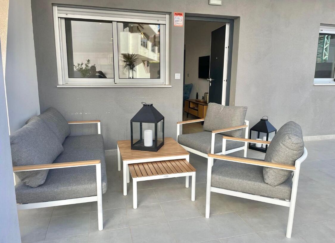 A modern living area with grey sofas and armchairs, a wooden coffee table, and a black lantern.