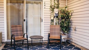 A covered porch with two wicker chairs and a small table, a sliding glass door, and a potted plant. - Cozy bungalow in the heart of historic Marysville (Marysville)
