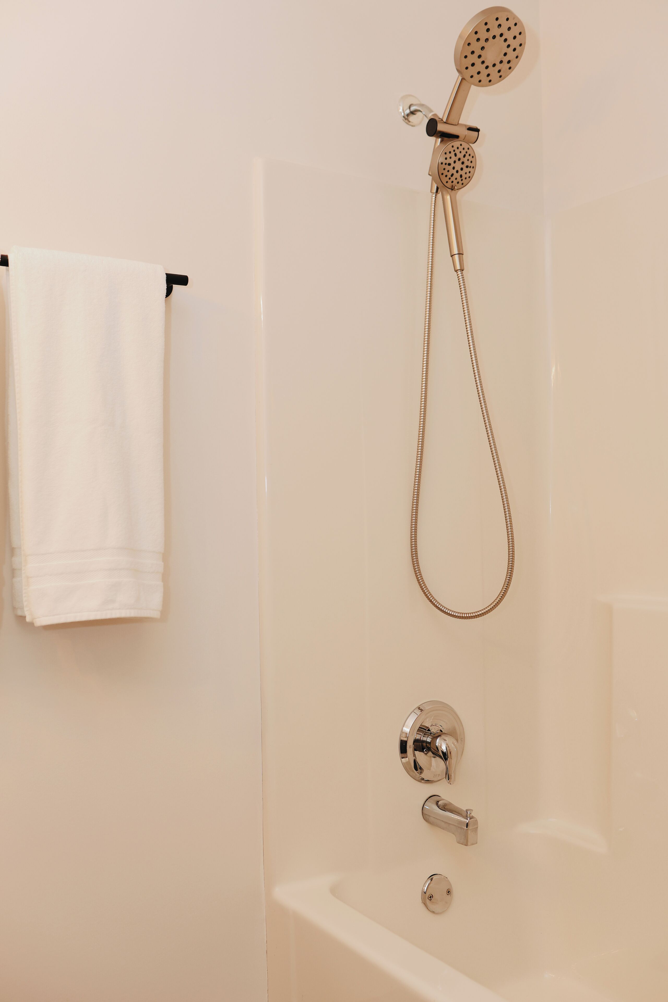A bathroom with a shower, a towel rack, and a bathtub.