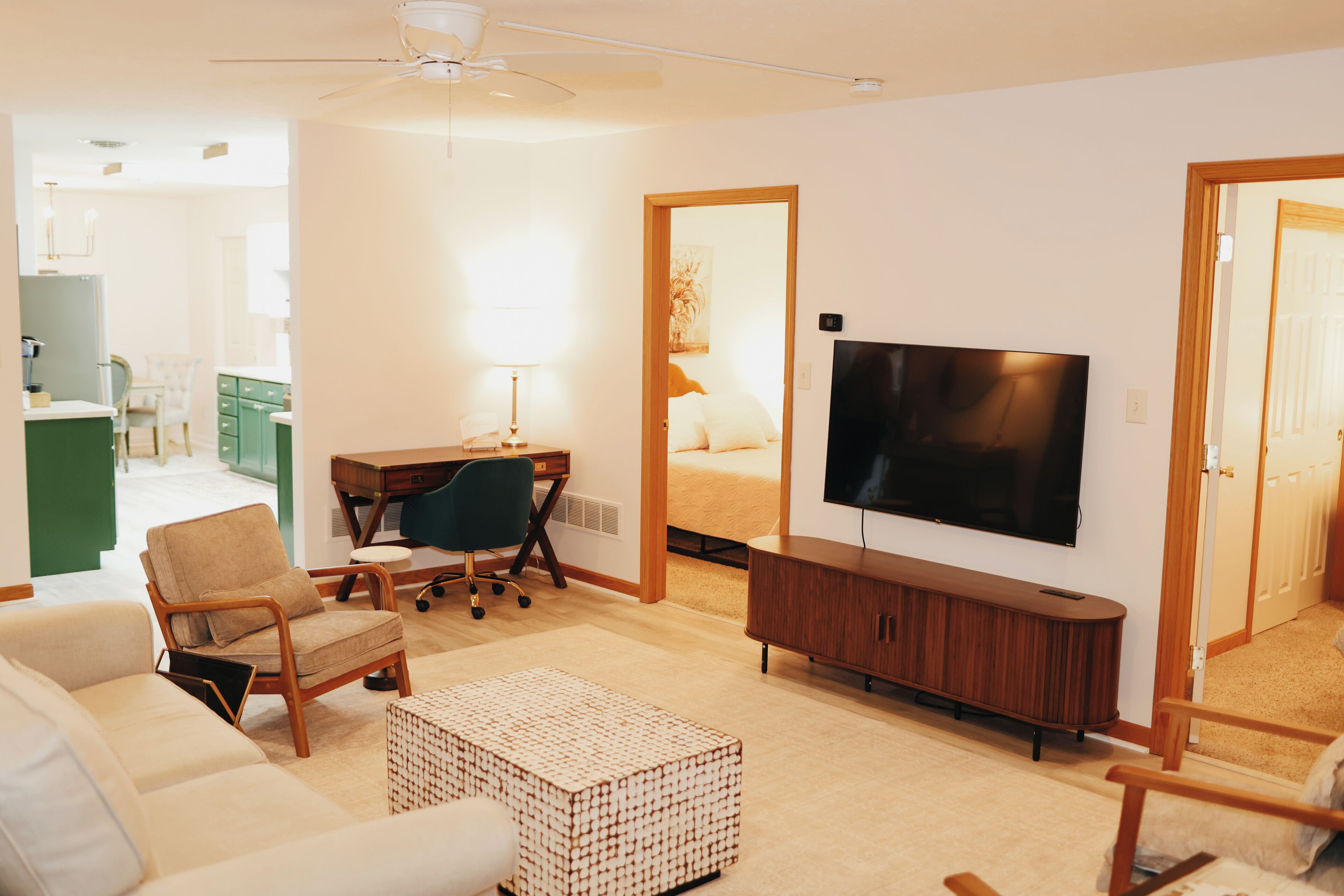 A modern living room with a sofa, a coffee table, a TV, and a desk with a chair.