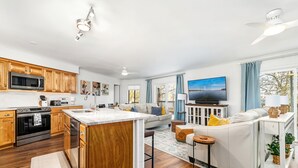 Une cuisine moderne avec des meubles en bois, un îlot central et un four à micro-ondes encastré.