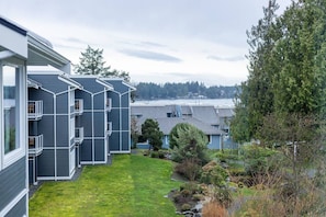 A residential building with multiple balconies, a well-maintained lawn, and a view of a body of water.