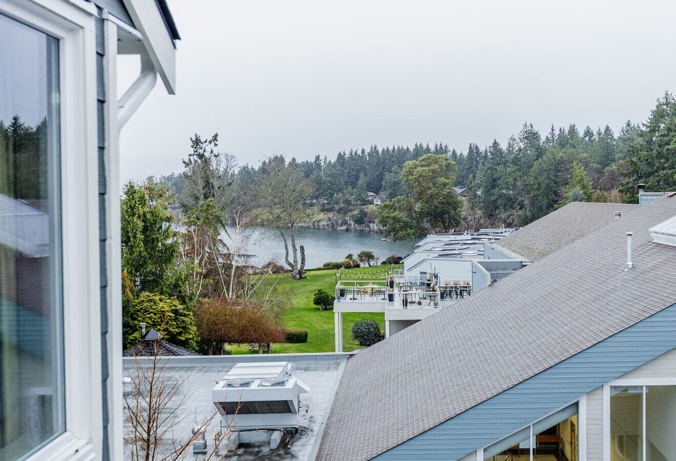 A residential building with a view of a lake, a covered outdoor area, and a sloped roof.