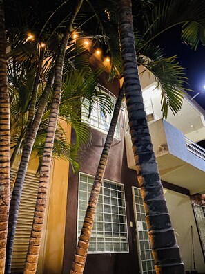 A building with a balcony, palm trees, and a window with blinds. - Comfortable and modern apartment, fully equipped in Acapulco Diamante zone (Acapulco)