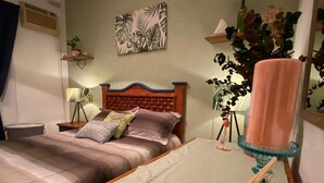 Une chambre à coucher avec un lit, des tables de chevet, une lampe et une étagère murale agrémentée d’une plante.