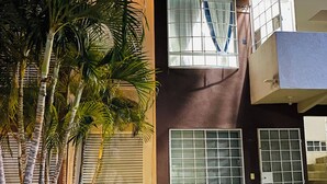 Une maison moderne à deux étages, dotée d’un balcon, d’une fenêtre avec un rideau et d’une pelouse bien entretenue.