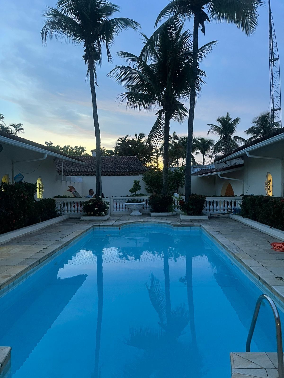 Une piscine bordée de palmiers et un bâtiment doté d’un toit en tuiles.