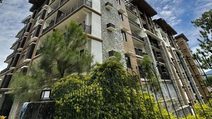 A multi-story residential building with balconies, a stone facade, and surrounding greenery. - Cherisia's Hideaway (Baguio)
