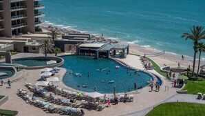 Um resort com uma grande área de piscina, acesso à praia e vista para o oceano.