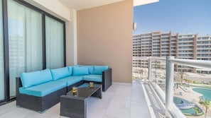 A balcony with a sectional sofa and a coffee table, overlooking a pool and high-rise buildings. - BeachFront |Las Palomas | RockyPoint | Sleeps 6 (Puerto Peñasco)