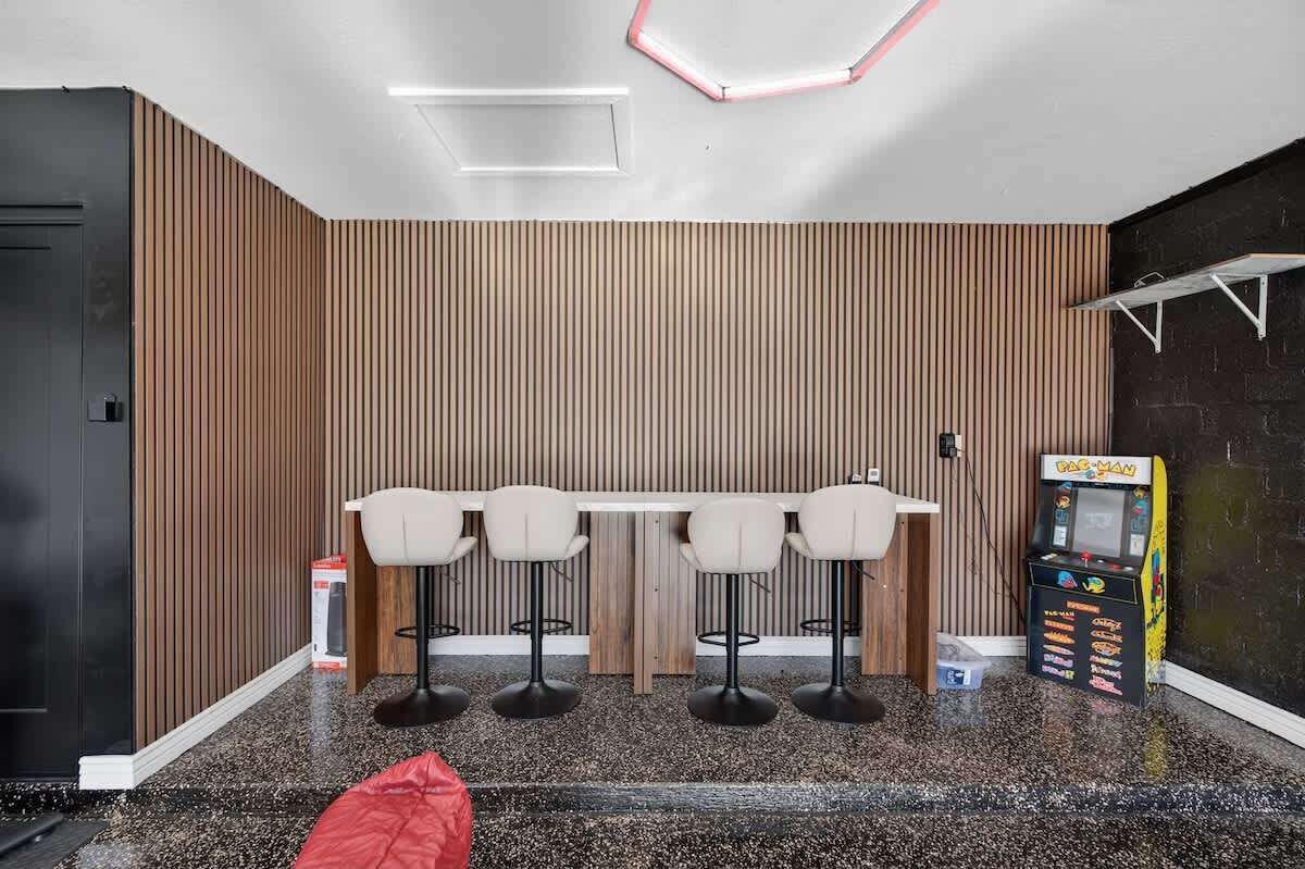 Un interior moderno con una zona de bar, asientos y una máquina de videojuegos Pac-Man.
