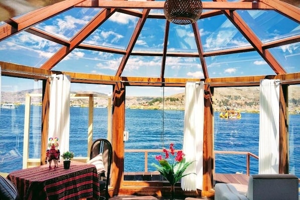 Una habitación con techo de madera y ventanas amplias que dan a una masa de agua.