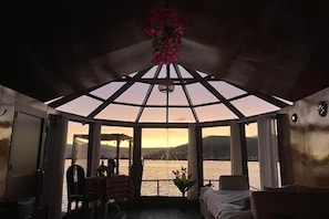 Una habitación con un amplio ventanal, una mesa con sillas y una cama.
