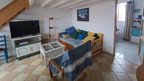A living room with a TV, sofa, and a glass-top table. - 42m² apartment for 4 people (BISCARROSSE)