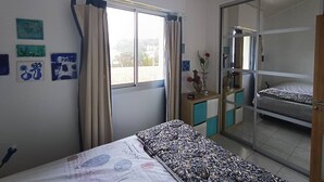 A bedroom with a bed, a bedside table with a vase, a mirror, and a sliding door leading to a balcony. - 42m² apartment for 4 people (BISCARROSSE)