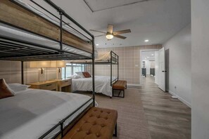 A hotel room with bunk beds, a ceiling fan, and a view of the hallway.