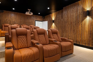 A home theater with multiple reclining leather chairs, wooden panel walls, and ceiling-mounted speakers.