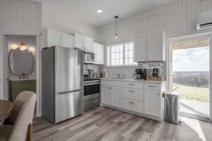 Una cocina moderna con armarios blancos, electrodomésticos de acero inoxidable y vistas al exterior.