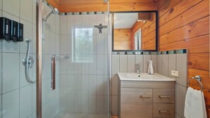 Une salle de bain avec une douche, un lavabo et un miroir.