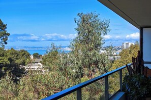 A balcony with a view of a coastal cityscape, including buildings and a body of water. - Appartement Floralia - Welkeys (Marseille)